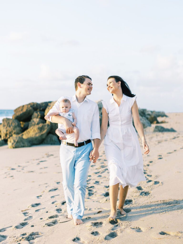 mom and dad walking holding hands with baby